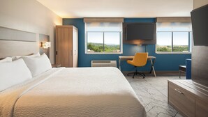 A hotel room with a large bed, a desk, a chair, a television, and a view of the outdoors. - Holiday Inn Express Morgantown by IHG (Morgantown)