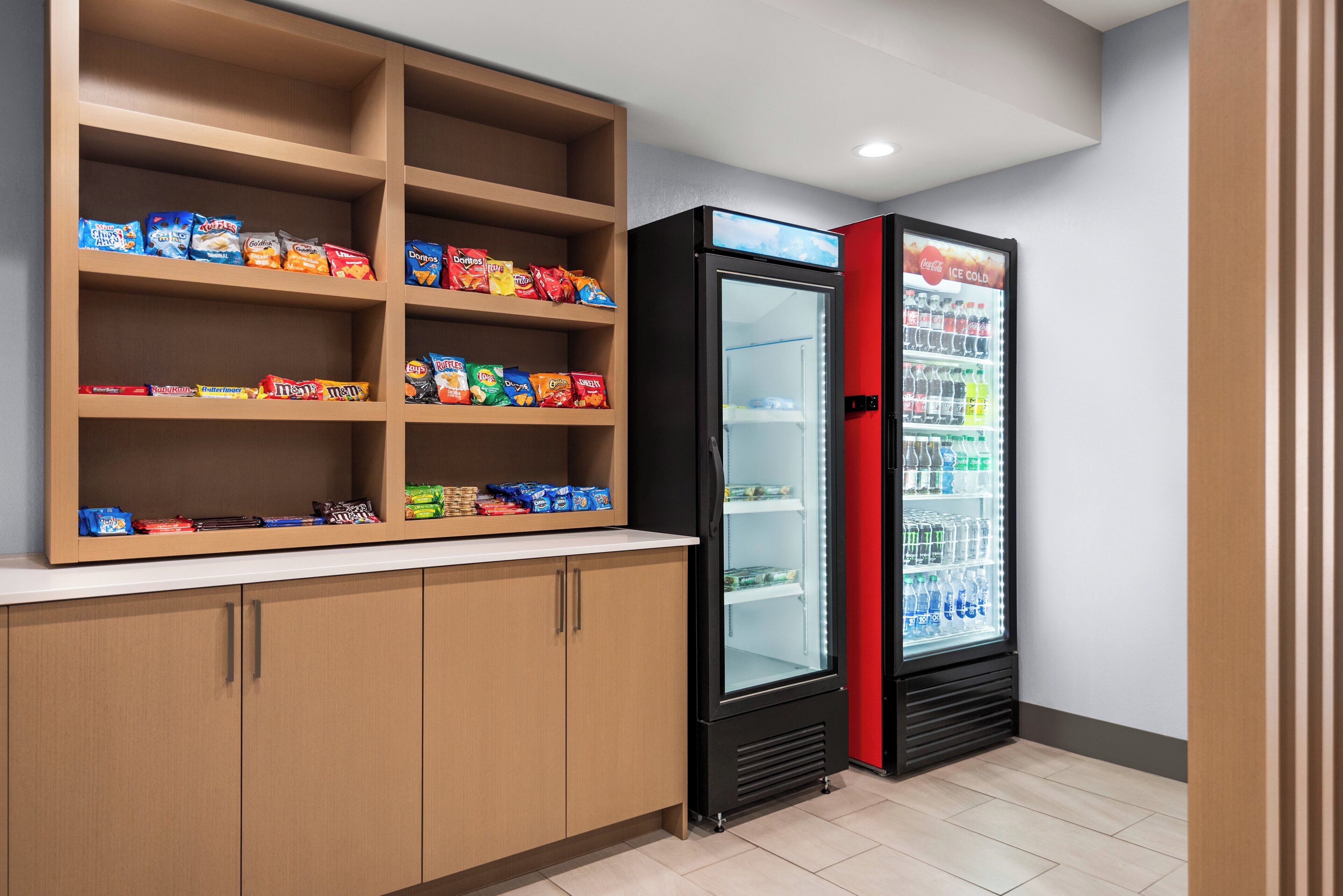 A snack shelf stocked with various chips and a Coca-Cola refrigerator.