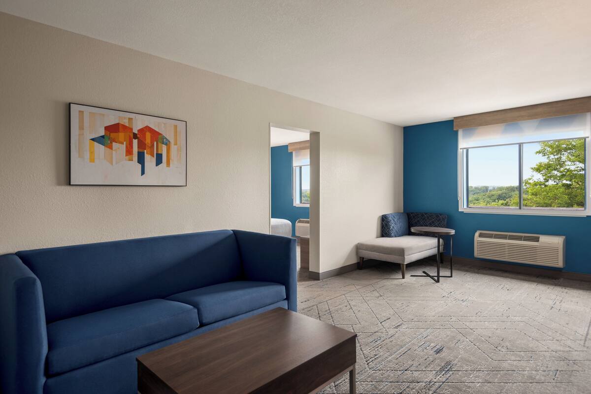 A modern room with a blue sofa, a small table, and a painting on the wall.