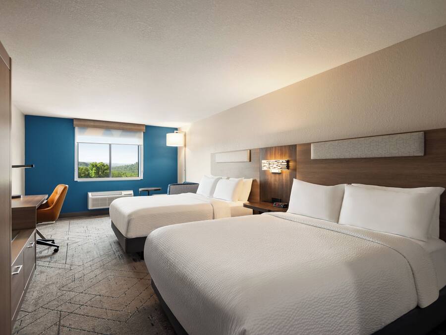 Ett hotellrum med två sängar, ett skrivbord, en stol och ett fönster med utsikt.