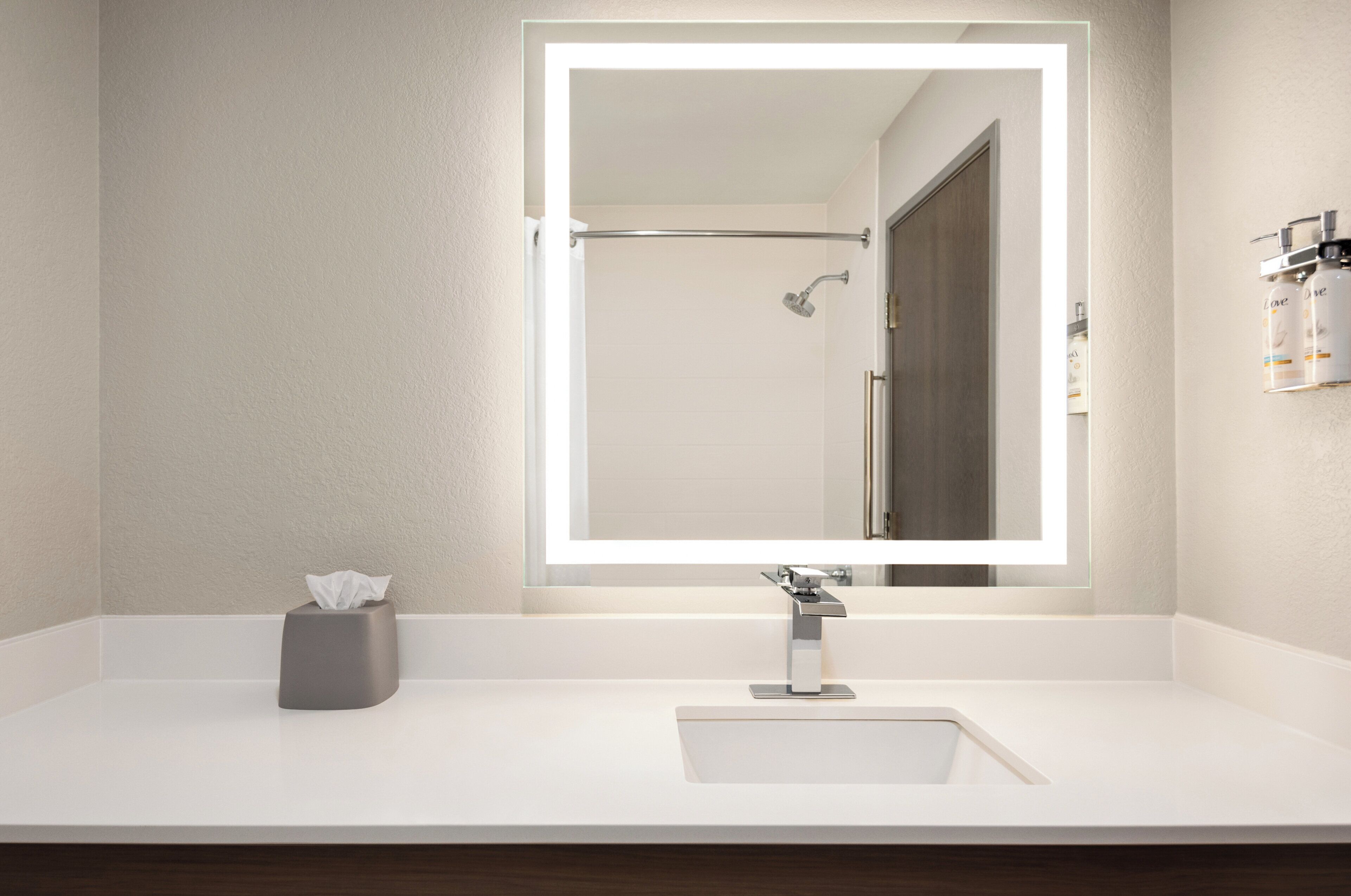 A modern bathroom with a large mirror, a shower, and a white sink.