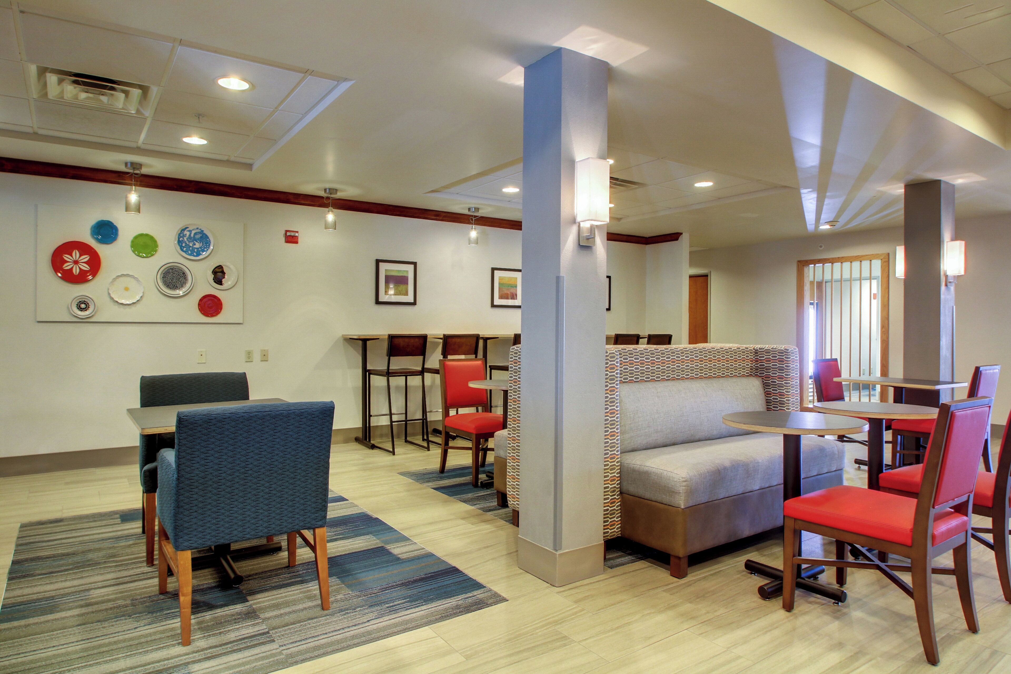 A hotel lobby with seating areas, a wall with decorative plates, and a ceiling with recessed lighting.