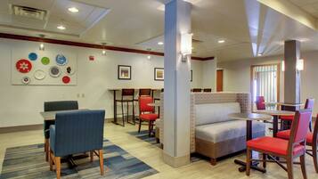 A hotel lobby with seating areas, a wall with decorative plates, and a ceiling with recessed lighting.