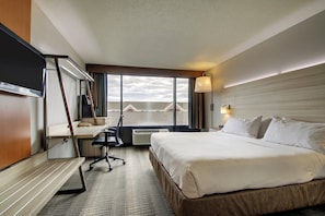A hotel room with a bed, desk, chair, and a large window with a view. - Holiday Inn Express Milwaukee North Brown Deer/Mequon by IHG (Milwaukee)