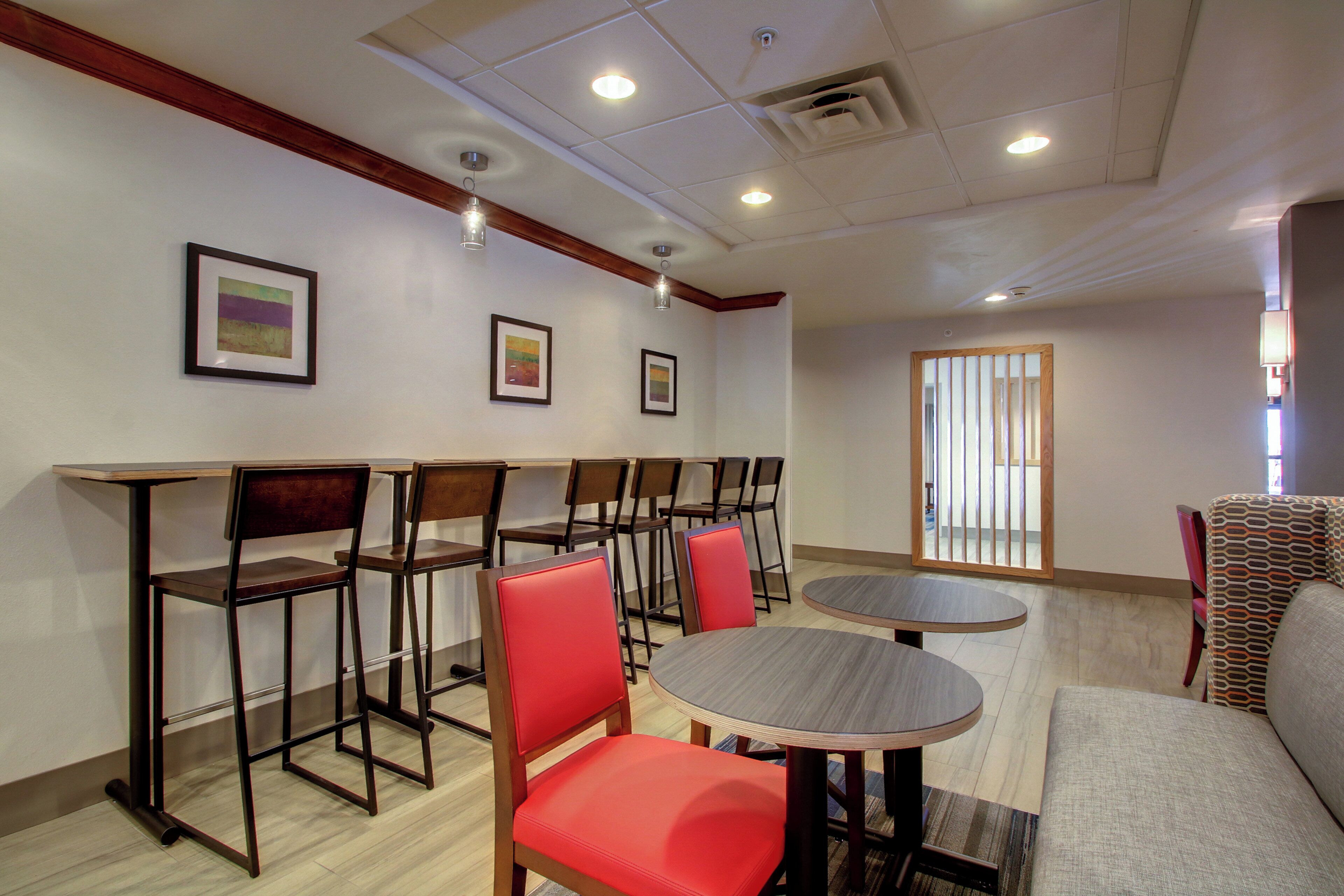 Habitación de hotel con comedor que incluye mesas, sillas, un sofá y obras de arte en las paredes.