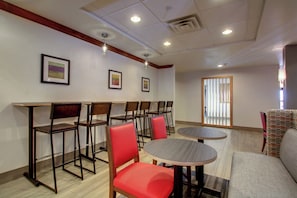 A hotel room with a dining area featuring tables and chairs, a sofa, and artwork on the walls. - Holiday Inn Express Milwaukee North Brown Deer/Mequon by IHG (Milwaukee)