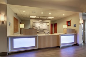A hotel reception area with a modern design, featuring a reception desk, a digital display, and a sign indicating a smoking-free environment. - Holiday Inn Express Milwaukee North Brown Deer/Mequon by IHG (Milwaukee)