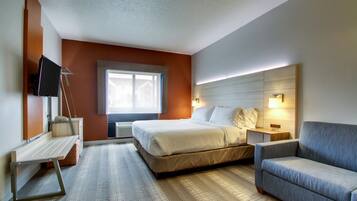 Habitación de hotel con cama, escritorio, silla, televisor y ventana.