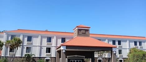 A hotel with a red-tiled roof, a covered entrance, and a symmetrical facade with multiple windows.