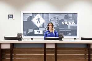 A reception desk with a cityscape view, a pedestrian crossing sign, and a 'Manager On Duty' sign. - Hampton Inn & Suites Chicago-North Shore/Skokie (Skokie)