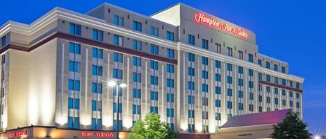A multi-story hotel with a prominent 'Hampton Inn & Suites' sign, a 'Ruby Tuesday' restaurant, and a 'Clearance 7-6' store.