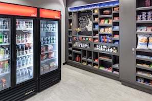 A beverage cooler with various drinks and a snack display with chips and candy. - Hampton Inn & Suites Chicago-North Shore/Skokie (Skokie)
