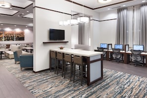 A modern hotel lobby with a bar area, seating, and a large TV screen. - Hampton Inn & Suites Chicago-North Shore/Skokie (Skokie)