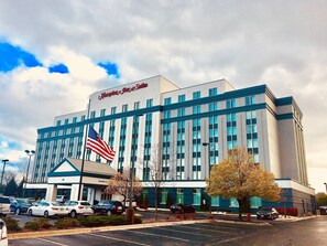 A hotel with a large American flag, multiple parking spaces, and a clear sky. - Hampton Inn & Suites Chicago-North Shore/Skokie (Skokie)