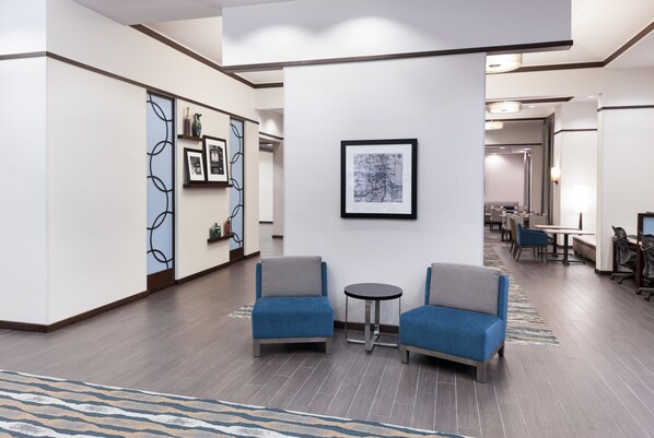 A modern lobby with two blue armchairs, a small round table, and a framed abstract artwork on the wall. - Hampton Inn & Suites Chicago-North Shore/Skokie (Skokie)