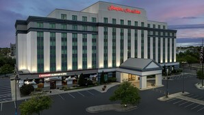 Un hotel grande con un letrero llamativo de Hampton Inn & Suites, un bar y restaurante Caribana Island, y un estacionamiento.