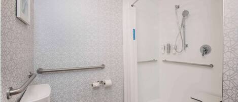 A modern bathroom with a shower, toilet, and handrails.