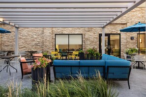 An outdoor patio with a stone wall, seating, and umbrellas. - Hampton Inn Dry Ridge (Dry Ridge)