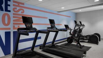 Un espacio de fitness con cintas de correr, bicicletas estáticas y una pared con mensajes motivacionales.