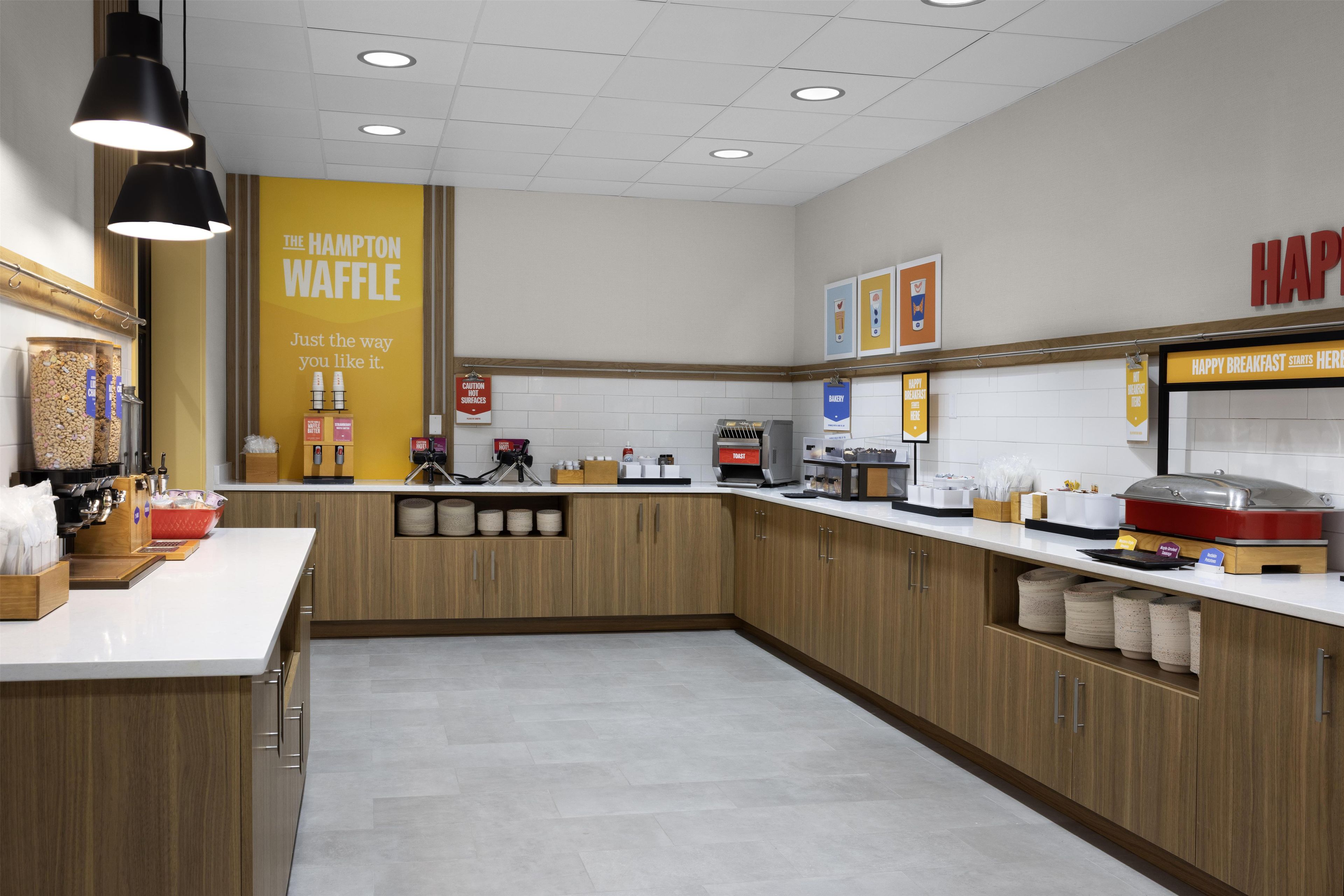 A modern kitchen with wooden cabinets, a white countertop, and various appliances.
