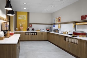 Una cocina moderna con armarios de madera, encimera blanca y diversos electrodomésticos.