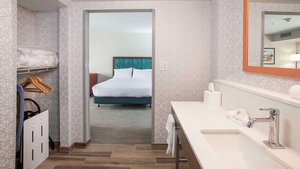 A hotel bathroom with a large mirror, a sink, and a shower area. - Hampton Inn Dry Ridge (Dry Ridge)