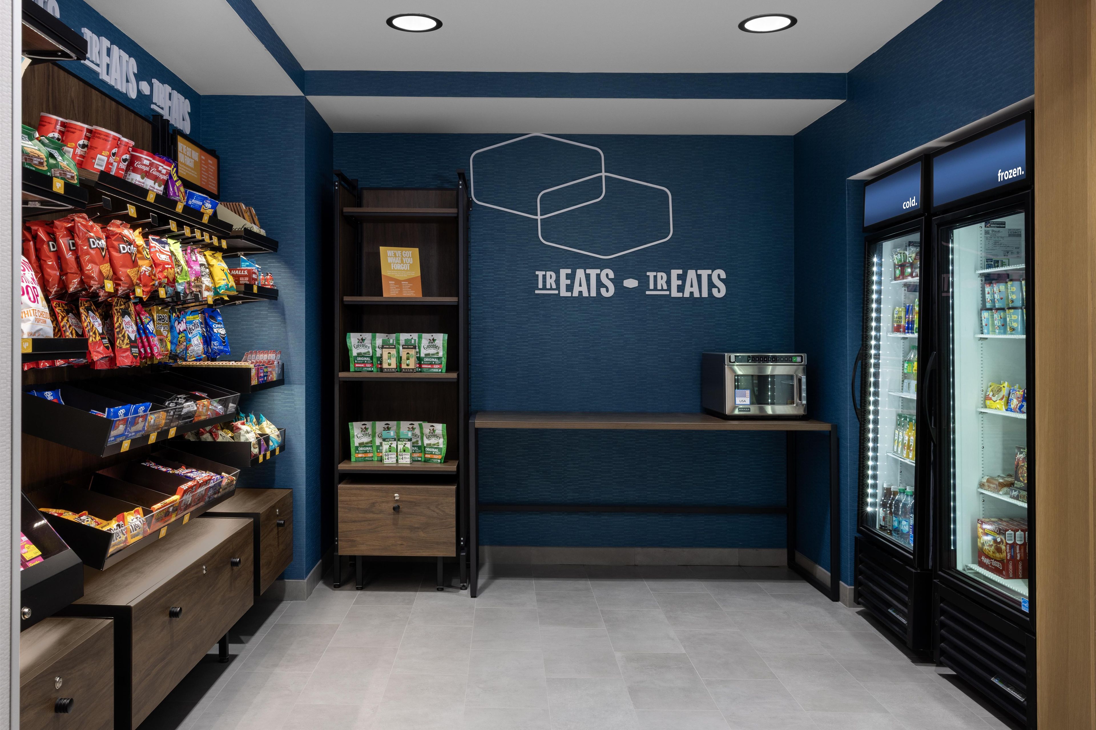Un espace dédié aux collations et aux aliments surgelés, avec des étagères remplies de diverses collations et un four à micro-ondes.