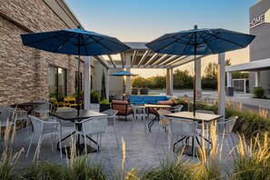 An outdoor patio with tables and chairs, umbrellas, and a stone wall. - Hampton Inn Dry Ridge (Dry Ridge)