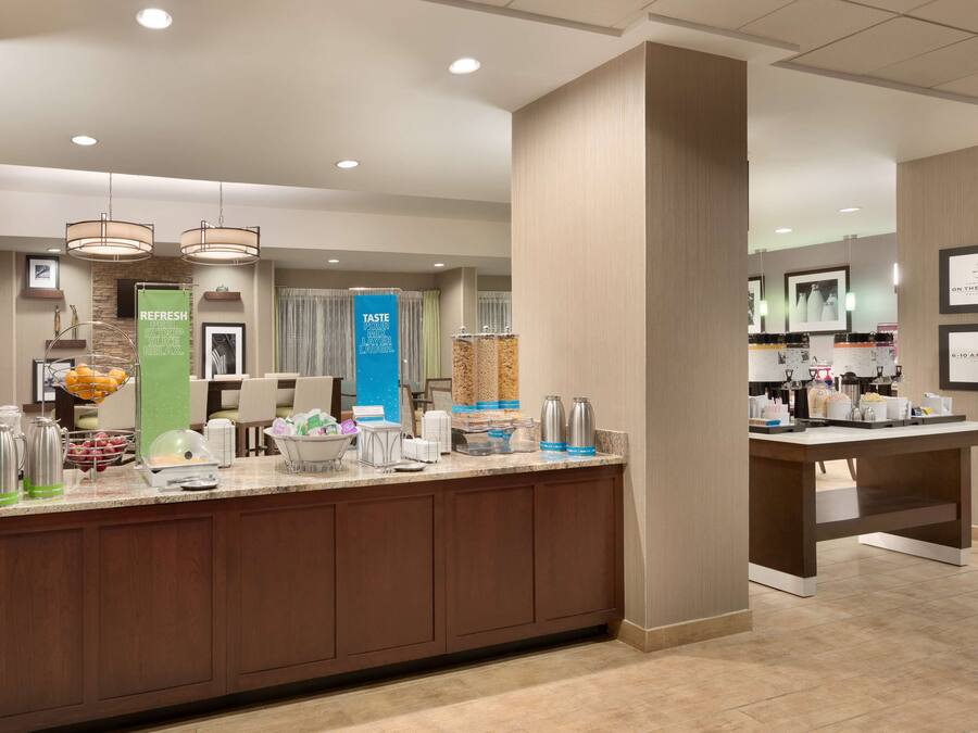 A hotel reception area with a counter, coffee machines, and a refreshment station.
