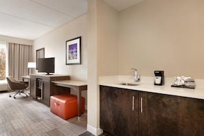 A hotel room with a desk, chair, television, and a kitchenette with a coffee maker and tea bags. - Hampton Inn Denville/Rockaway/Parsippany (Denville)