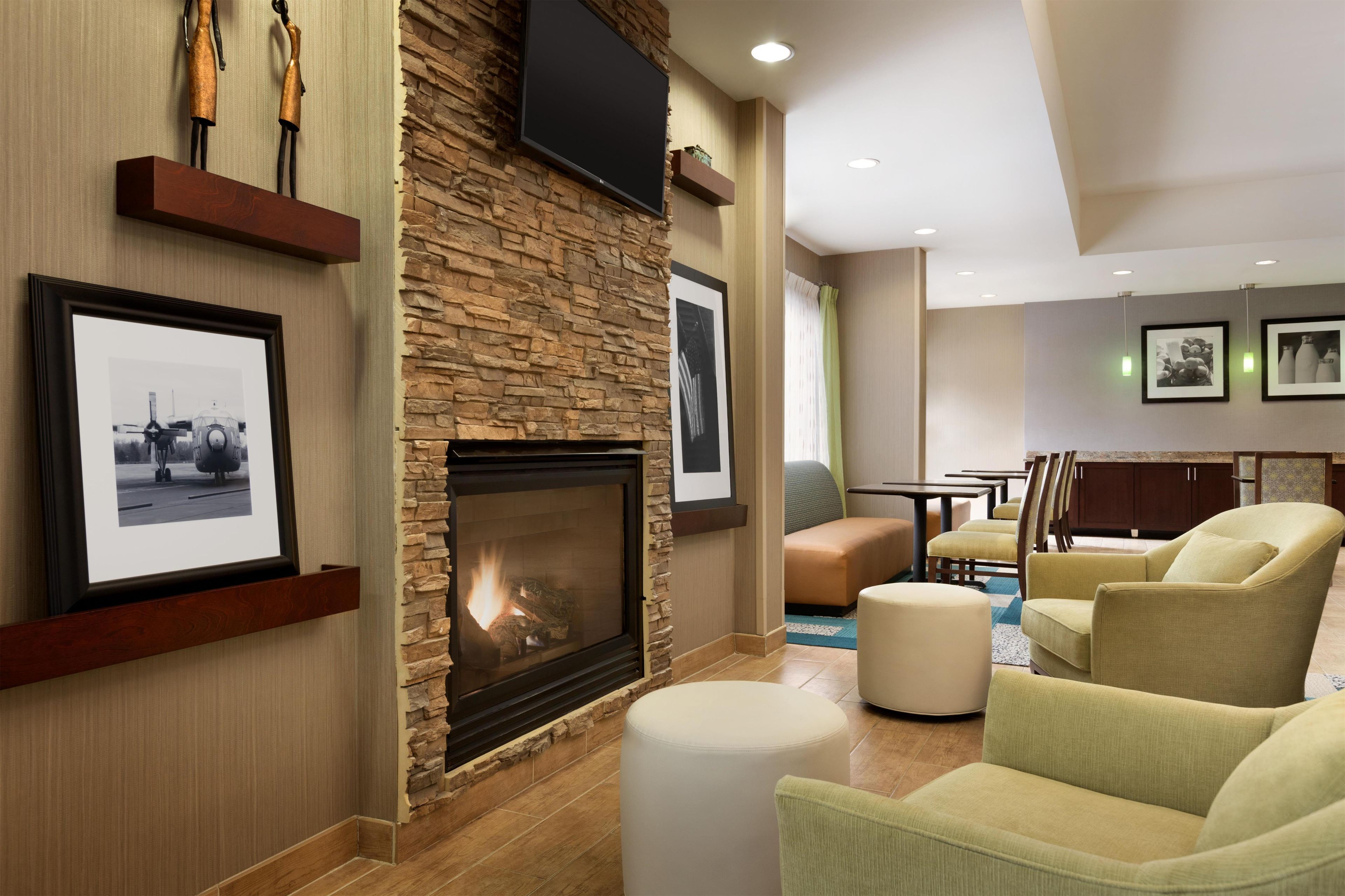 A hotel lobby with a fireplace, seating area, and artwork on the walls.