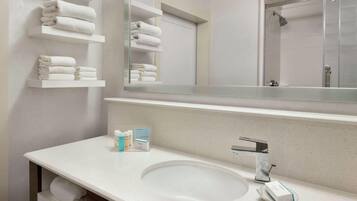 A modern bathroom with a large mirror, white sink, and towel racks.