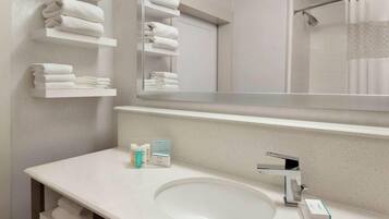Un baño moderno con un lavabo grande, un espejo y estantes con toallas dobladas.