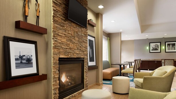 A modern living room with a stone fireplace, comfortable seating, and framed artwork on the walls. - Hampton Inn Denville/Rockaway/Parsippany (Denville)