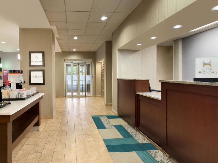 A hotel reception area with a counter, framed artwork, and a view of the entrance.