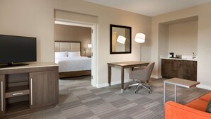 A hotel room with a bed, a desk, a chair, a television, a mirror, and a sofa. - Hampton Inn Denville/Rockaway/Parsippany (Denville)