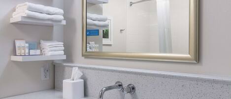 Un baño moderno con un espejo grande, toallas blancas en estantes, un lavabo y una zona de ducha.