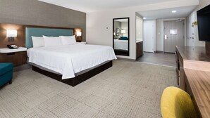 Une chambre d’hôtel avec un grand lit, des tables de chevet, un bureau et une télévision.