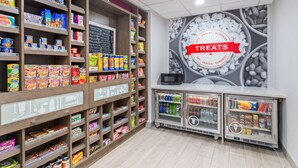 Un espace dédié aux collations et aux gourmandises, avec des étagères remplies de divers en-cas, un tableau noir servant de menu et un four à micro-ondes.