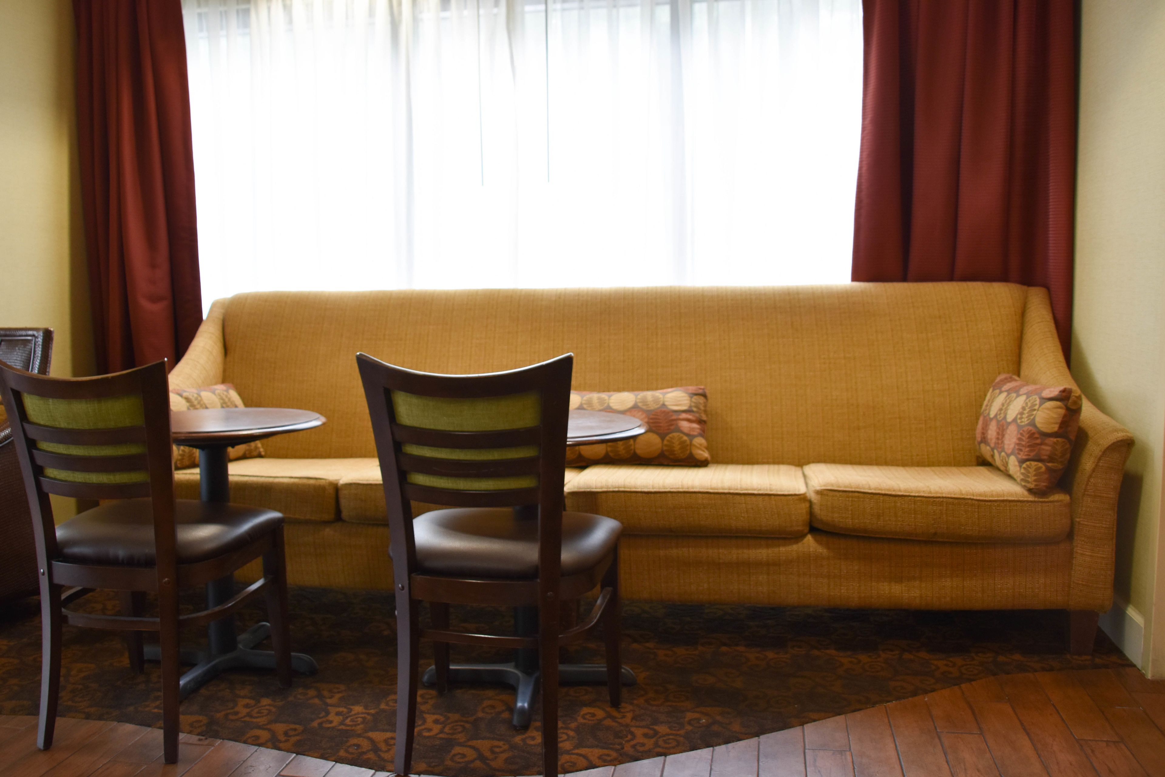Una sala de estar con un sofá, dos sillones, una mesita redonda y un tapete estampado.