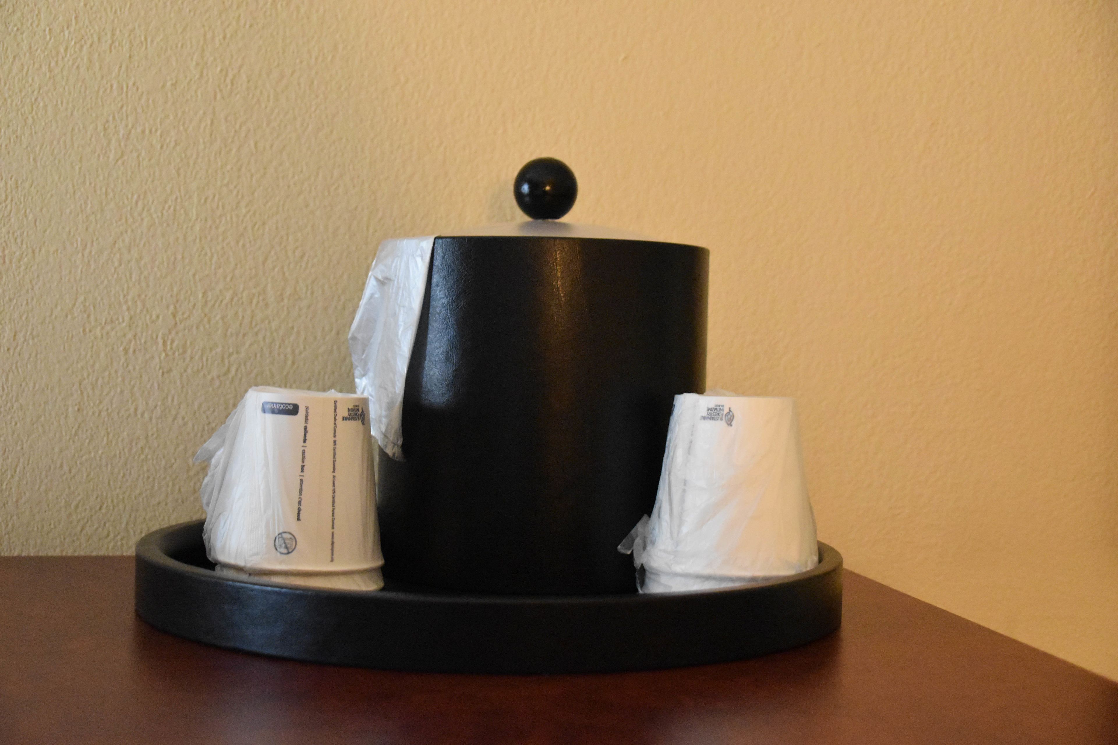 A black cylindrical container with a lid, two white tissue boxes, and a black spherical object on top of the container.