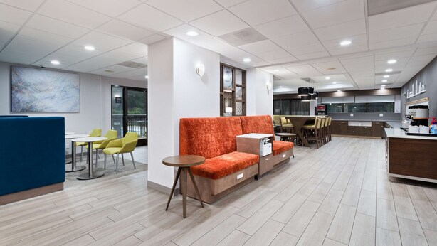 Un intérieur moderne comprenant un canapé, des fauteuils, une petite table et un coin cuisine.