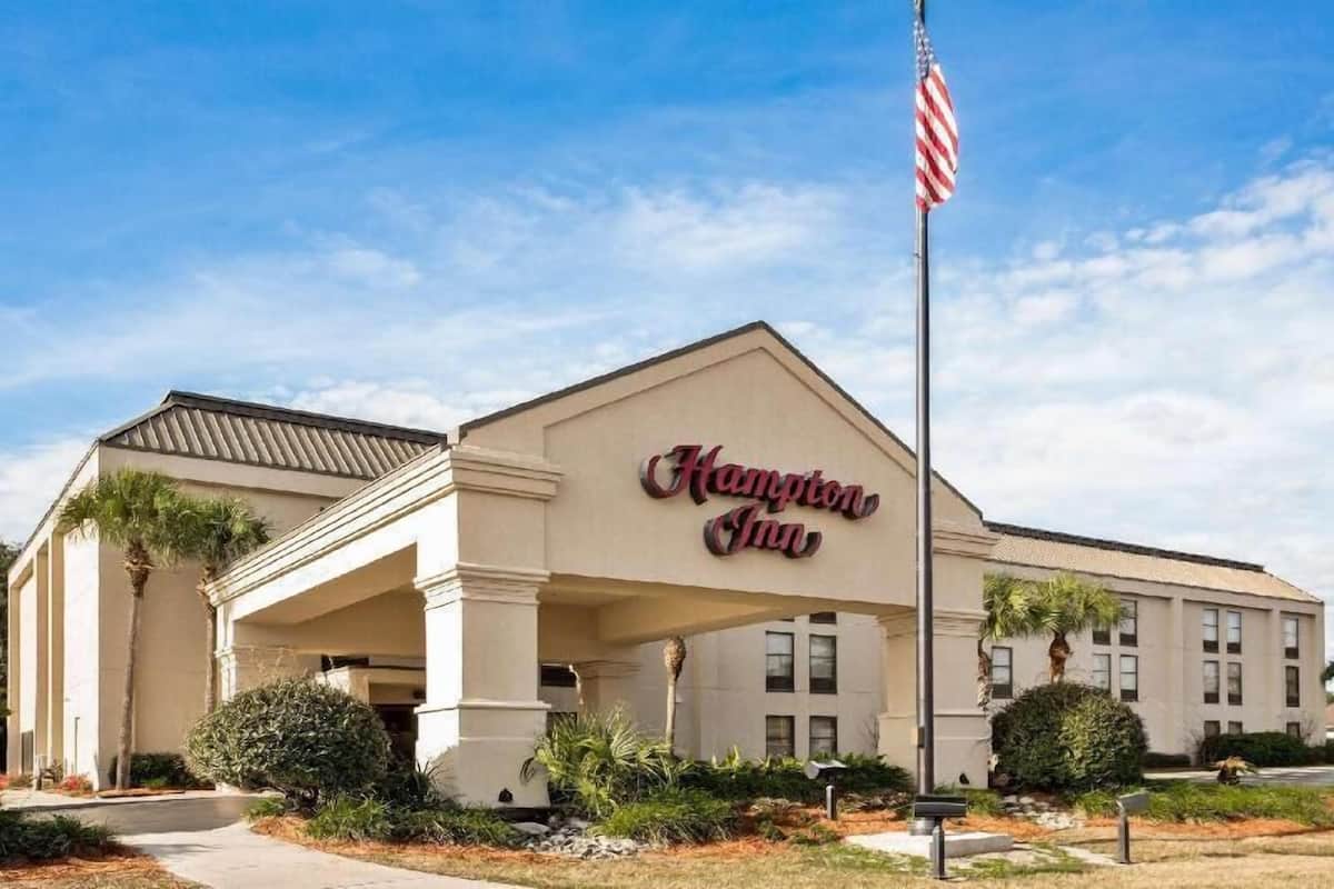 A Hampton Inn hotel with a classic architectural style, featuring a prominent entrance and an American flag.