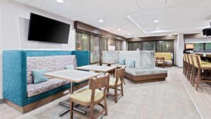 Un hall d’hôtel moderne, doté d’espaces aménagés avec des sièges, d’un téléviseur à écran plat et de grandes fenêtres.