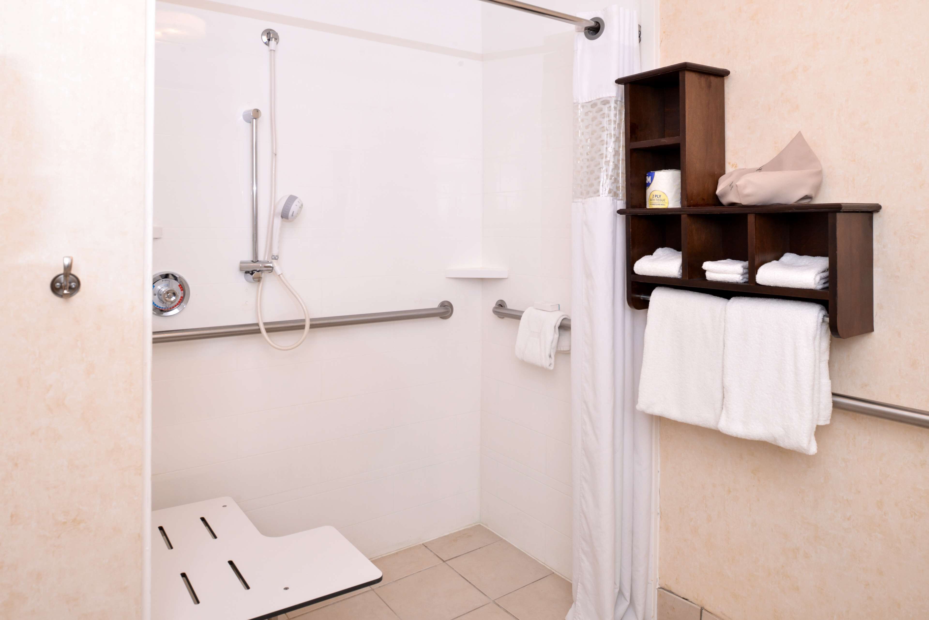 Un baño con ducha, inodoro y toallero.