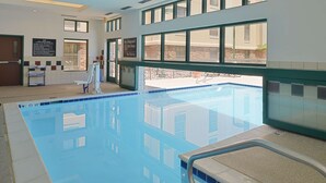 Une piscine intérieure à l’eau d’un bleu limpide, dotée d’un poste de surveillance pour les sauveteurs et d’un panneau indiquant l’absence de sauveteur.