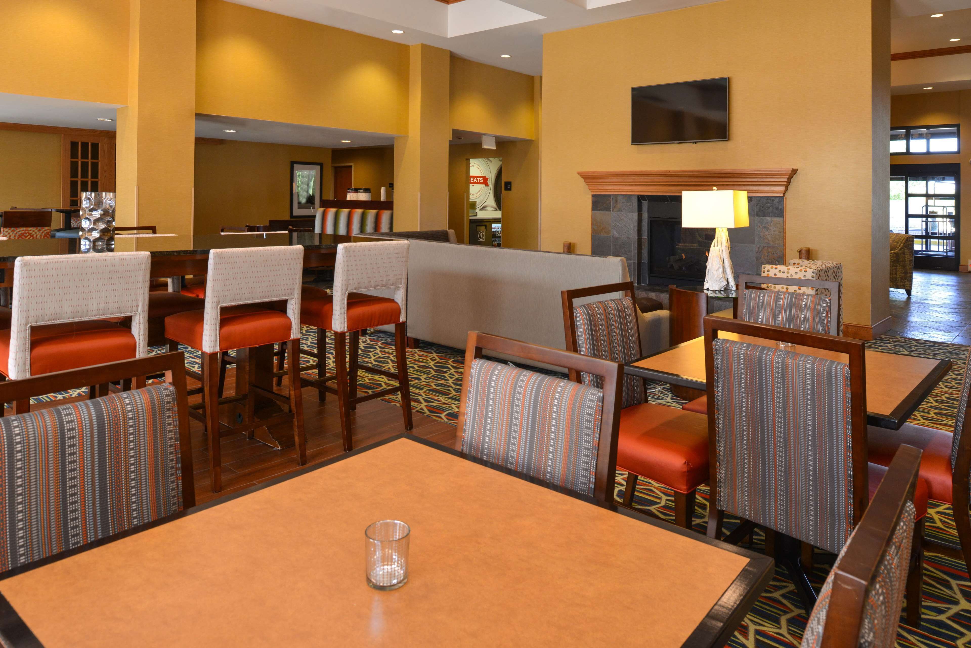 A hotel lobby with multiple seating areas, a fireplace, and a television mounted on the wall.