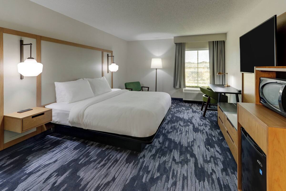 Een hotelkamer met een groot bed, nachtkastjes, een bureau, een stoel en een televisie.