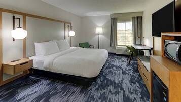 Une chambre d’hôtel avec un grand lit, des tables de chevet, un bureau, une chaise et un téléviseur.
