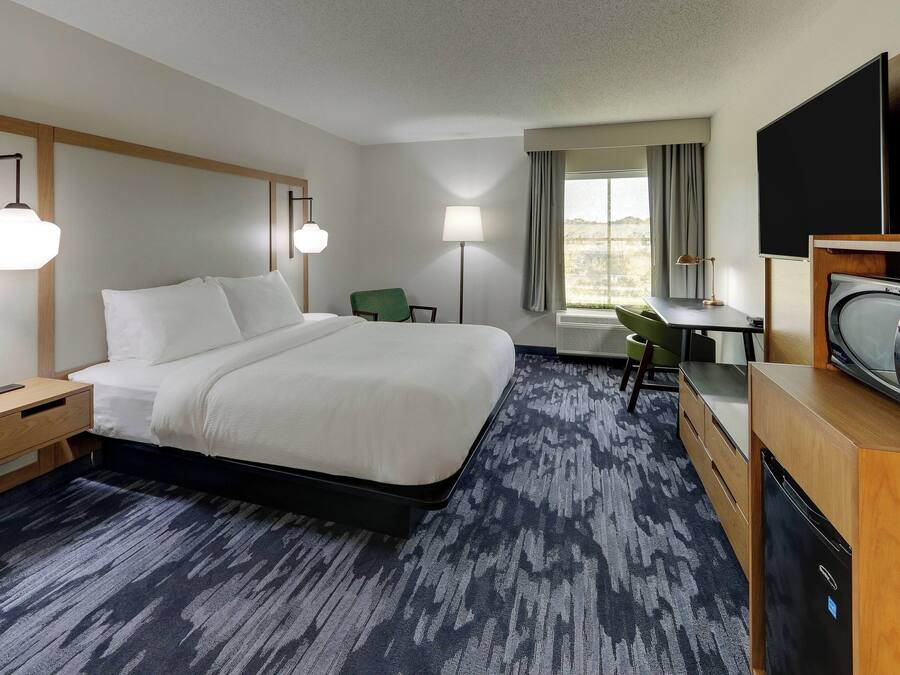 Une chambre d’hôtel avec un grand lit, des tables de chevet, un bureau, une chaise et un téléviseur.
